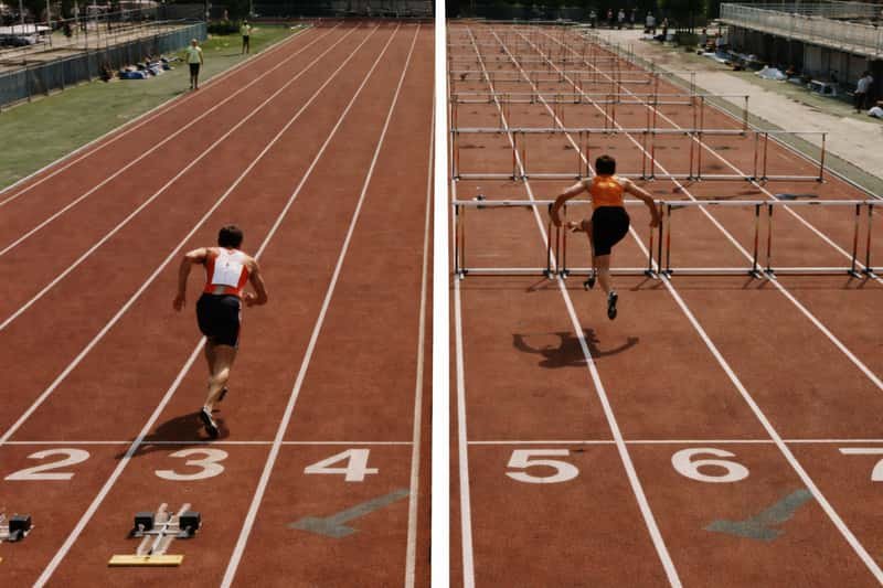Overhead view of a running track showing 100m sprint lane marked with white lines and hurdles race lane with ten evenly-space