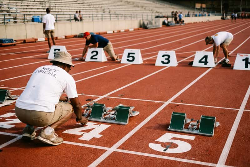 Overhead view of a running track showing numbered lane markers and staggered starting blocks positioned at different distance